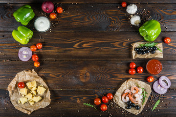 Food background design. Frame of seafood, shrimps and olives on a dark wood. Pizza ingredients.