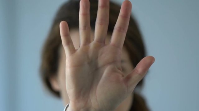 Unhappy depressed woman showing stop gesture, standing with outstretched hand