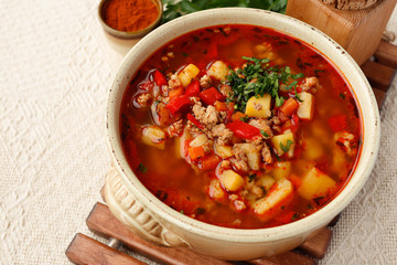Bulgarian potato soup with paprika and minced meat in a ceramic bowl