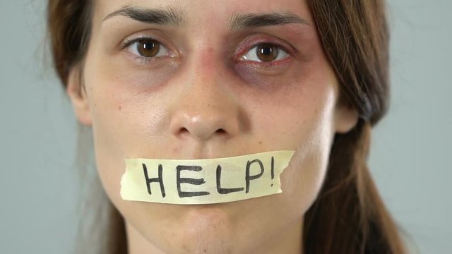 Help message on taped mouth of bruised woman, helpless silent abuse victim