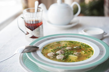 Dietary soup with chicken meatballs and stalks of celery and aromatic herbs and potatoes