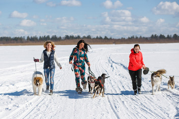 Three happy girls owners playing with their dogs in winter nature.