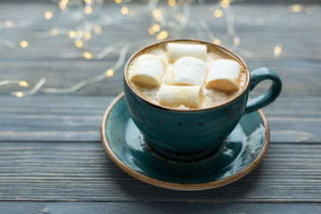 Cup of coffee, marshmallow on wooden background. Warm lights. Cozy winter morning.  Lifestyle concept. Selective focus.