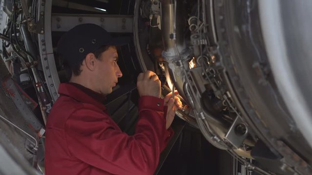Engine passenger aircraft maintenance. Engineer checks the engine of the aircraft. The repair of aircraft in the hangar. Maintenance of aircraft. Start the jet engine. 4k