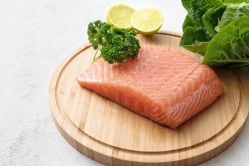 raw salmon fillet, lettuce and lemons on a wooden kitchen board, copy space