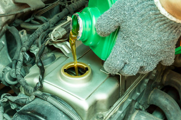 Close up of pouring new oil to old car engine.