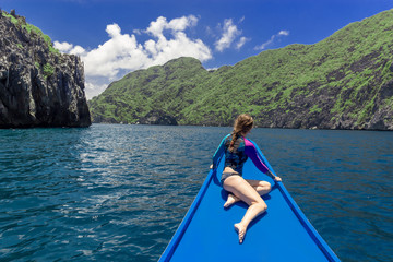 Fototapeta na wymiar Back view of the young woman relaxing on the boat and looking at the island. Travelling tour in Asia: El Nido, Palawan, Philippines.