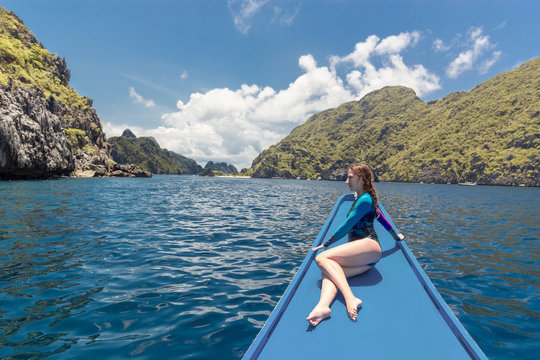 Young woman on the boat and looking forward into lagoon. Travelling tour in Asia: El Nido, Palawan, Philippines.