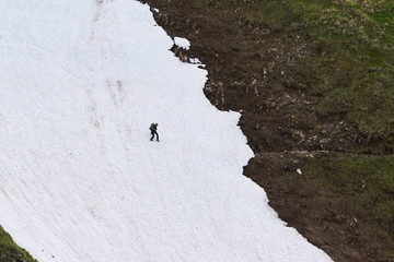 Bergwanderer überquert ein steiles Schneefeld