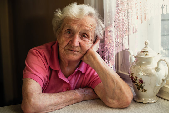Portrait of an elderly woman sitting in the house.