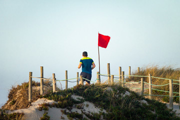 Obraz premium Male Runner Passes By Red Flag on Boardwalk