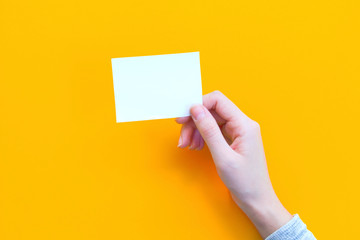 woman hand holding paper on orange background.