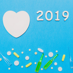 Pharmaceutical background Christmas and new year 2019. Pills, ampoules and a wooden heart on a blue background. pharmacy and healthcare concept