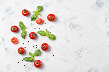 Fresh cherry tomatoes with basil leaves and black pepper on a stone table, vegetable pattern, top view with copy space