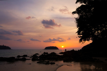 Fototapeta na wymiar Trees and island silhouettes on tropical beach at vivid sunset time