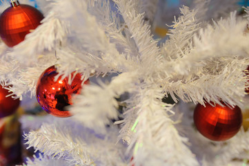 Closeup photo of red Christmas balls hanging on a white tree