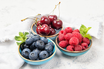 Assorted fresh juicy berries. Cherry, blueberry and raspberry in bowls