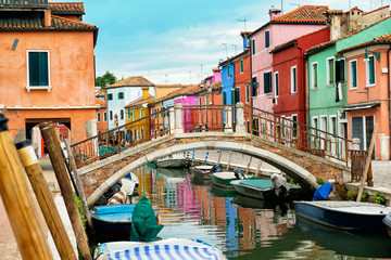 Fototapeta na wymiar Beautiful street with canal, bridge, boats and multicolored houses, Burano island, Venice, Italy