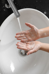 Fototapeta premium Little boy washing hands with soap over sink in bathroom, above view