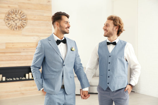 Happy newlywed gay couple in suits at home