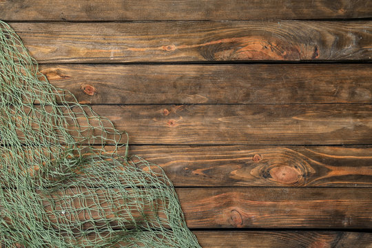 Fishing net on wooden background, top view with space for text