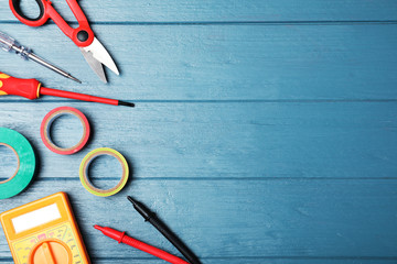Flat lay composition with electrician's tools and space for text on wooden background