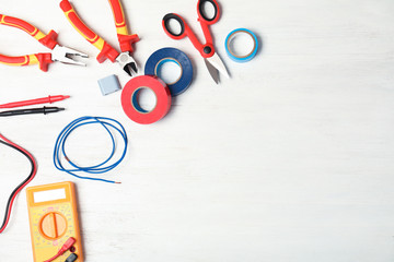 Flat lay composition with electrician's tools and space for text on wooden background