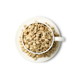 Cup and saucer with green coffee beans on white background, top view