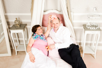 The couple is lying on the bed and holding the baby's clothes. Conception of pregnancy. © Fox