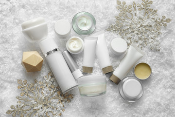 Set of cosmetic products on decorative snow, flat lay. Winter care