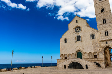 The beautiful Romanesque Cathedral Basilica of San Nicola Pellegrino, in Trani. Construction in limestone tuff stone, pink and white. A pointed arch under the bell tower. Italy, Puglia, Bari, Barletta