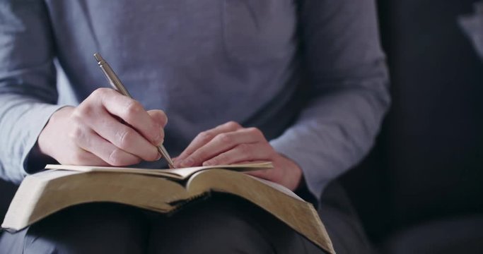 Dolly shot of a woman studying the Bible and praying at home.