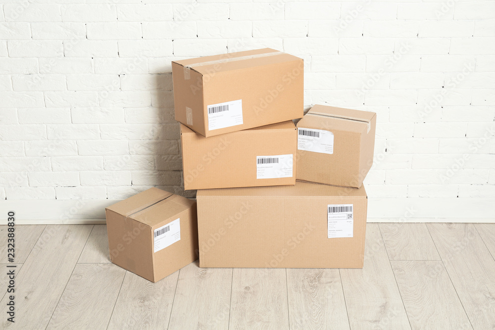 Poster Stack of parcel boxes on floor against brick wall