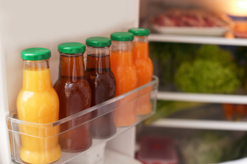 Open refrigerator with bottles of different juices