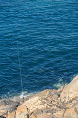 View at the waters sea and cliff of rocks, with fishing rods and head of a fisherman, on the coast of Leca da Palmeira