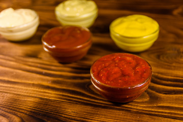 Different sauces in glass bowls on wooden table