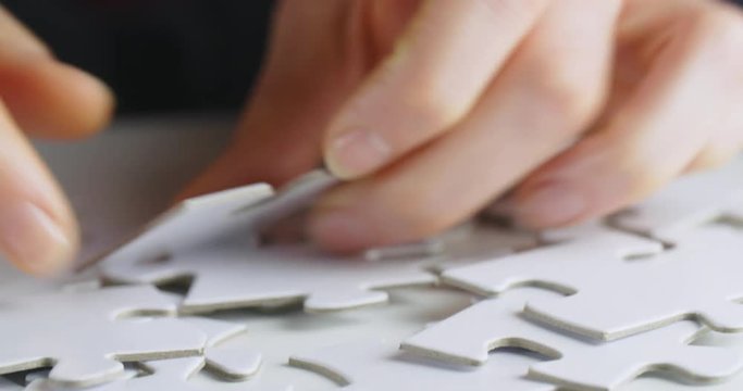 Female hands looking for and finding a piece of a jigsaw puzzle.