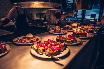 Chef and cook prepared orders guacamole avocado toasts and fresh pancakes with fruits on order counter in restaurant