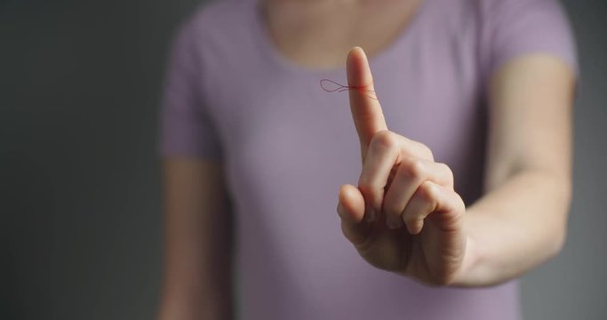 Woman showing a finger with a reminder knot on it.