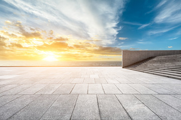 Empty square floor and dramatic sky with coastline at sunset