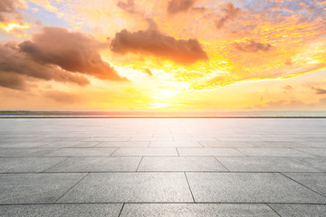 Empty square floor and dramatic sky with coastline at sunset