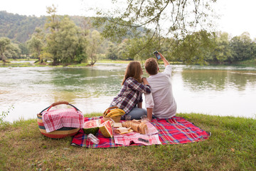 Couple taking a selfie by mobile phone while enjoying picnic time