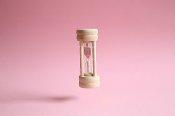 Hourglass floating on pink background. Business deadline, last second or time out concept