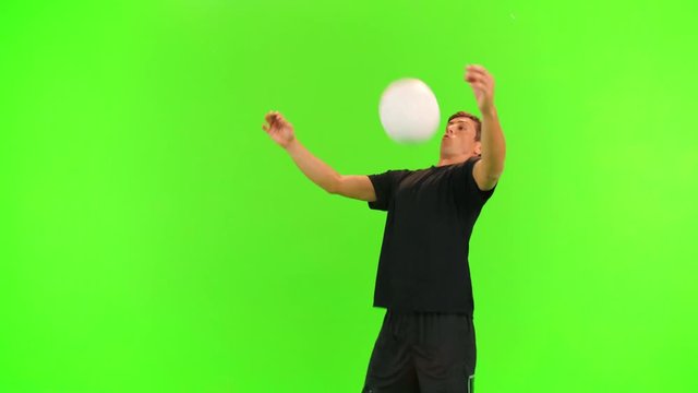 Soccer player receives and passes a ball with his shoulder and head over a green screen, 2 takes, slow motion.