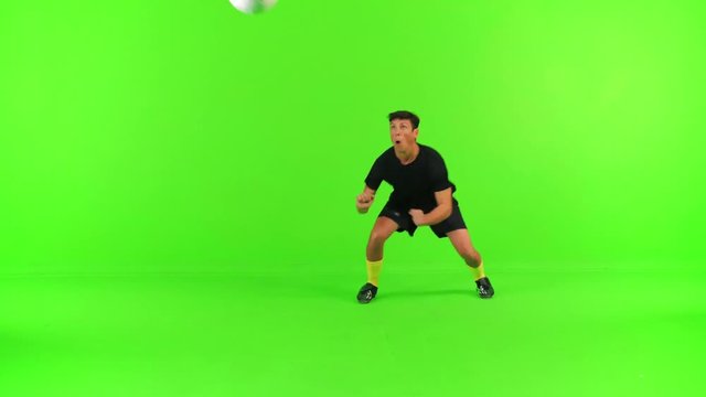 Soccer player prepares for a header, jumps and passes the ball over a green screen, high speed shutter, 4k.