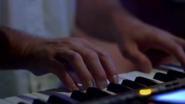 Closeup of synth player during concert. Slowmotion shot of musician playing synthesizer on wedding reception.