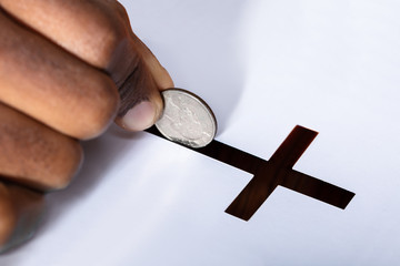 Person Inserting Coin In Crucifix Slot