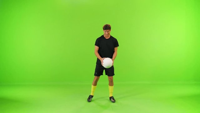 Soccer player does a Neck Stall, winks and play with a ball, slow motion over a green screen, high speed shutter, slow motion, 2 takes.
