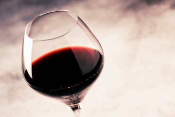Red wine from grape varieties merlot in glass, gray table, selective focus, shallow DOF