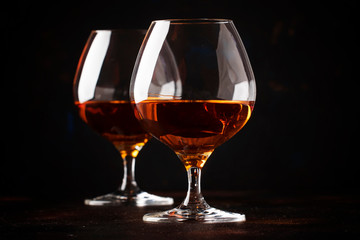Grape brandy in shot glass, dark brown background, selective focus